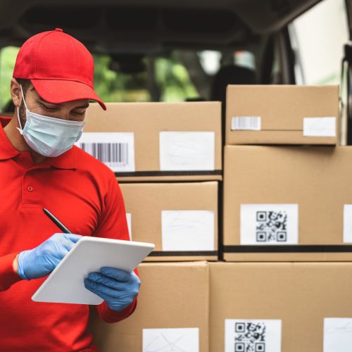 Delivery man wearing face protective mask to avoid corona virus spread - Young express courier working during coronavirus outbreak - Deliver and online buying concept